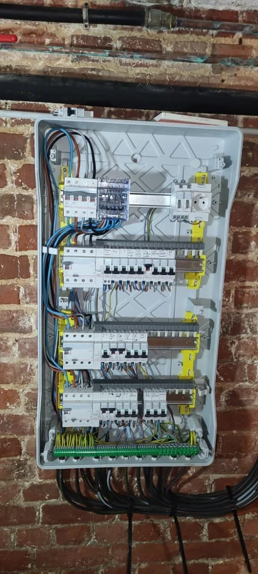 Tableau électrique et protections modulaires installés lors d'une rénovation, sur mur en briques
